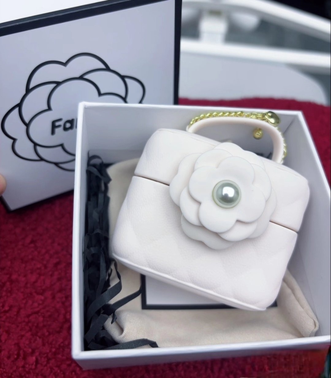 开箱:白色礼盒内衬里放着的小香包玩具,山茶花造型扣子特写