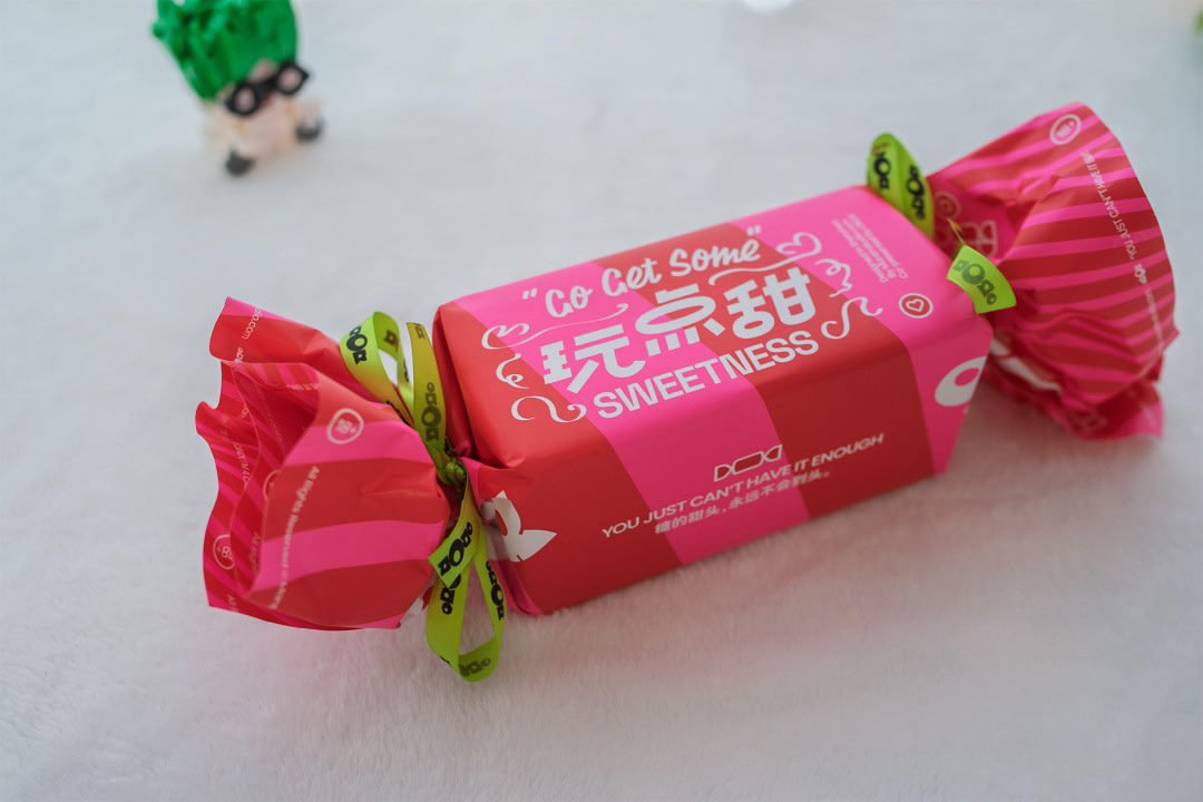 礼盒细节:粉色盒身上的糖果图案与绿色提带装饰