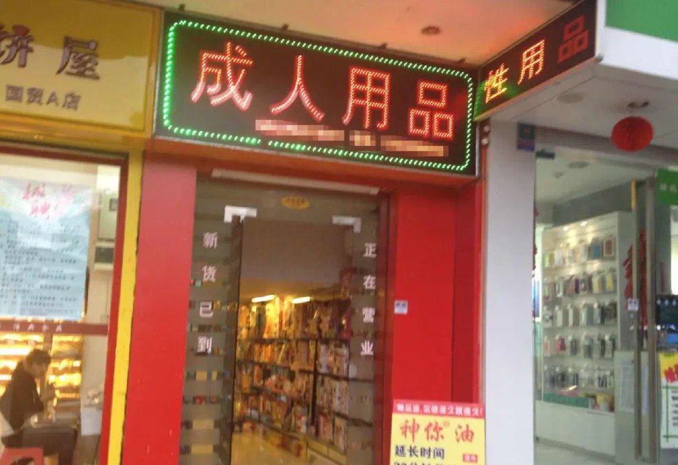 街边成人用品店门面,暖光灯箱映着夜色